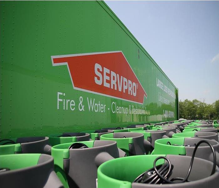 SERVPRO logo on a large green container positioned to the right with trees and the sky to the left.
